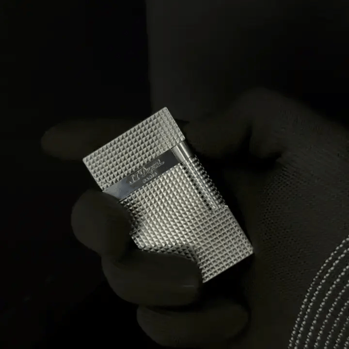 A close-up view of a silver lighter held in a gloved hand